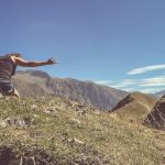 a man standing on top of a lush green hillside